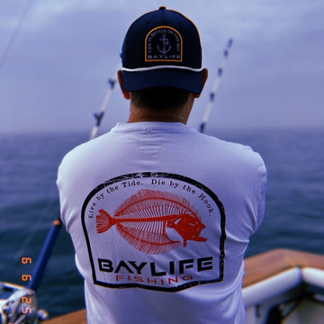 Maryland rockfish performance fishing long sleeve t-shirt in royal blue and white camo Richardson SnapBack hat riding a boat in the Chesapeake Bay. 